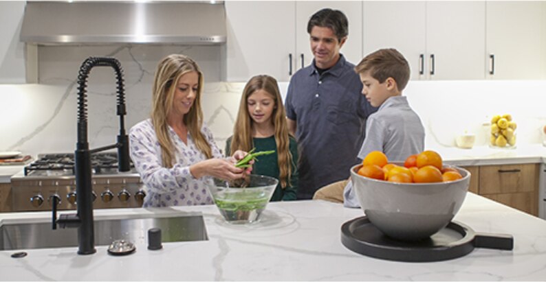 Family of four preparing vegetables together at a kitchen island