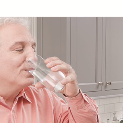 Drinking a glass of water at the kitchen counter