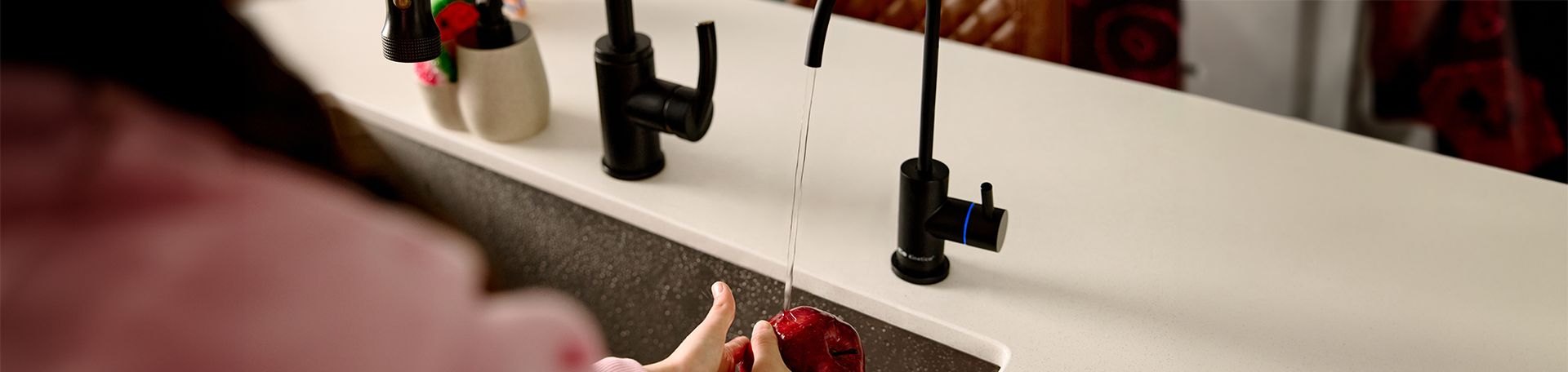 Rinsing fruit under a black Kinetico drinking water faucet