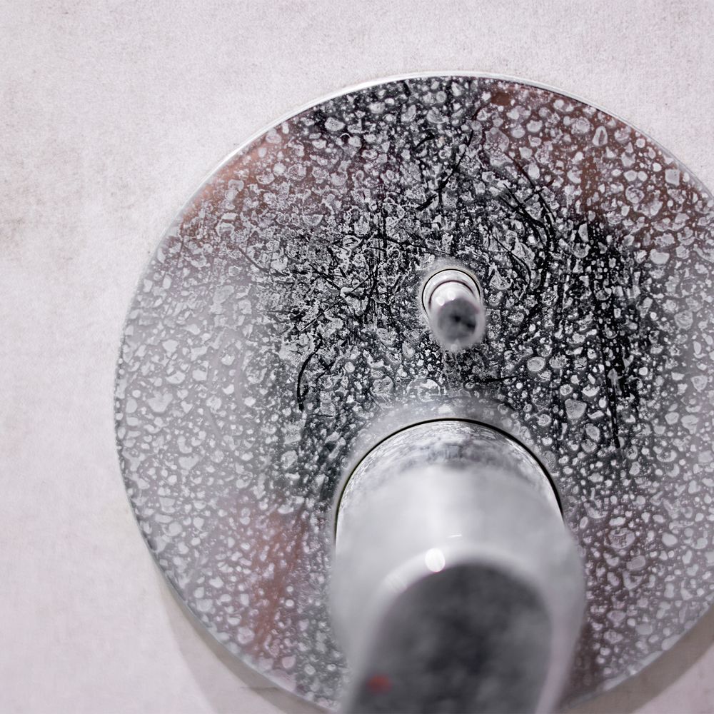 Hard water scale spots on a chrome shower valve