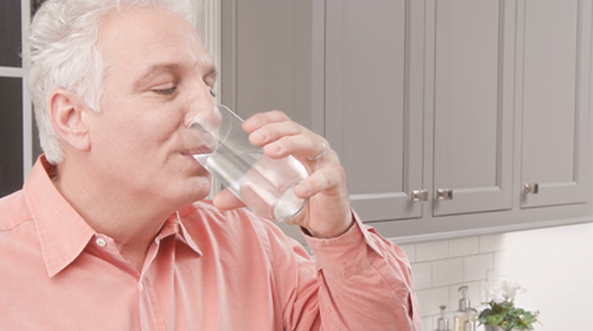 Drinking a glass of water at the kitchen counter