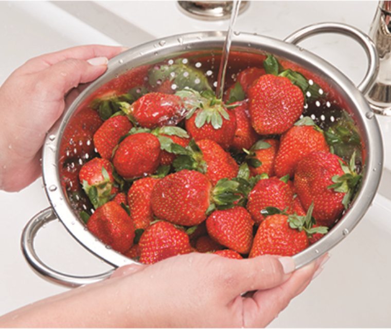 Rinsing fresh strawberries under the kitchen tap