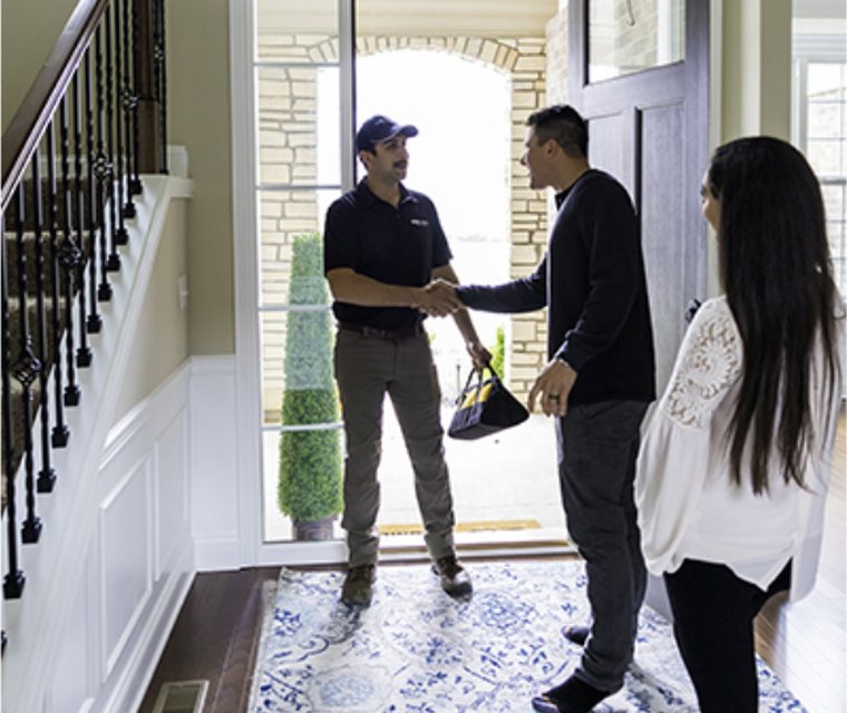 A Cardinal Water technician greeting homeowners at their front door