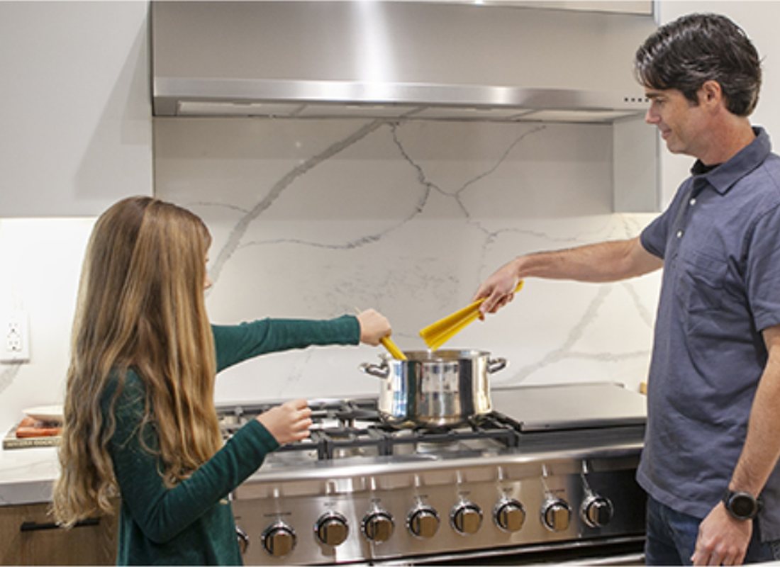 A father and daughter cooking at the stove