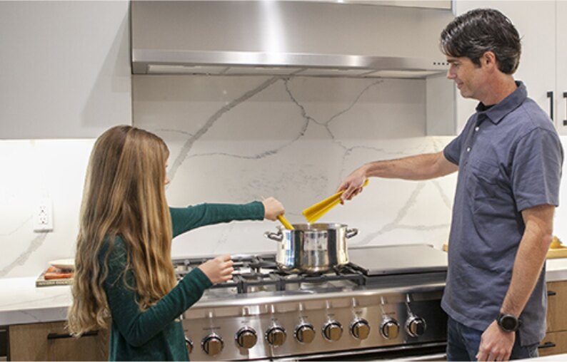 Father and daughter cooking together at the stove