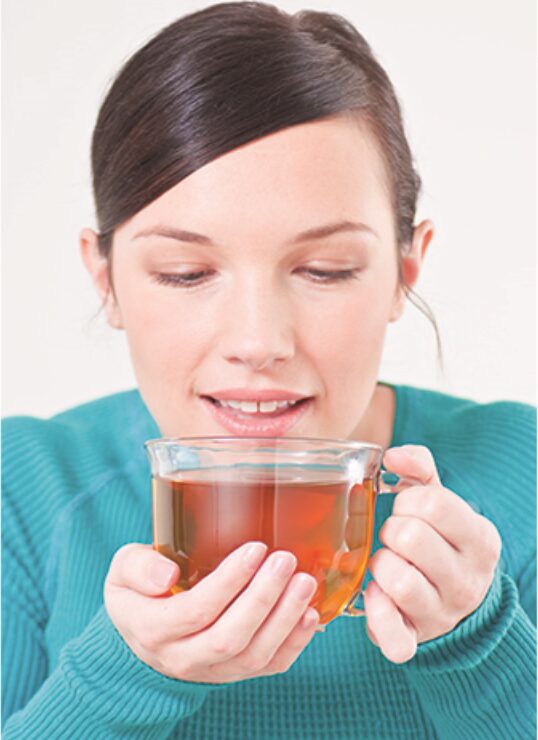 Woman warming her hands around a cup of tea in the evening