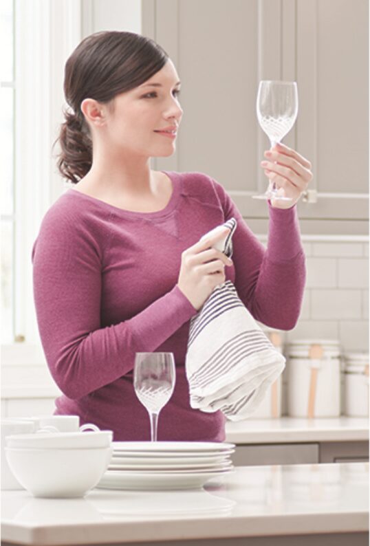 Woman admiring a sparkling clear wine glass fresh from the dishwasher
